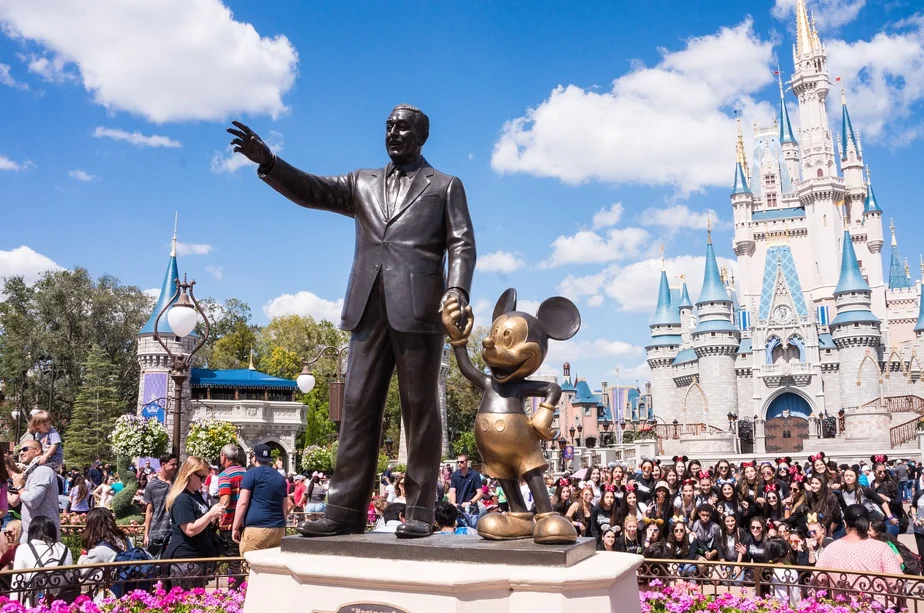 Estátua de Walt Disney de mão dada com o Mickey, fazendo referência a comprar ações da Disney.