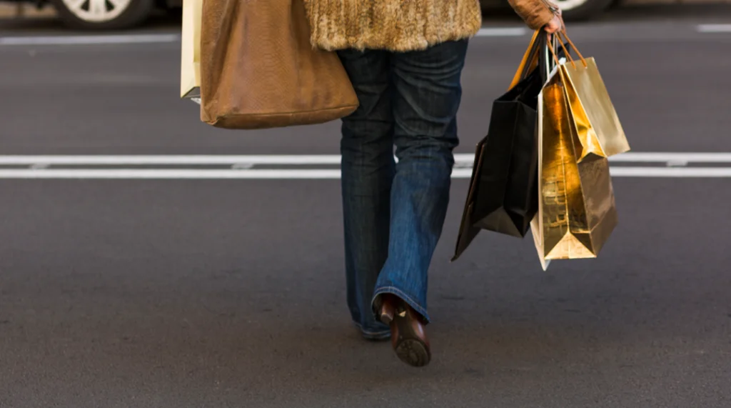 Pessoa caminhando com sacolas de compras representando o consumo na economia influenciado pela taxa Selic.