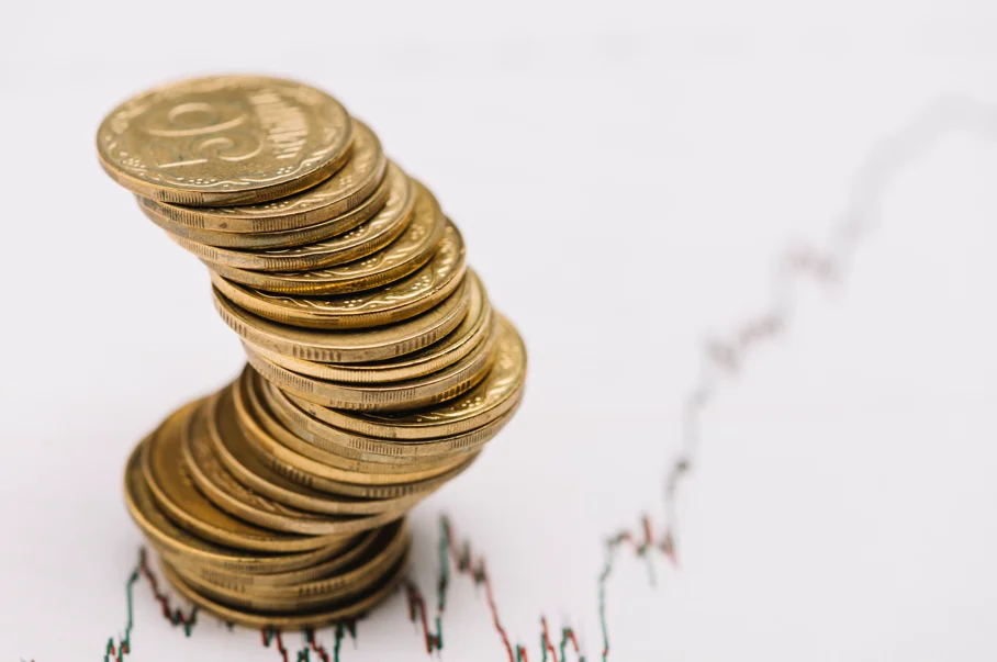Pilha de moedas sobre gráfico financeiro representando investimentos influenciados pela taxa Selic.