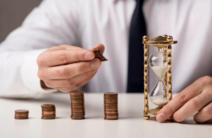 Proteger patrimônio: vista frontal de um empresário com moedas e ampulheta.